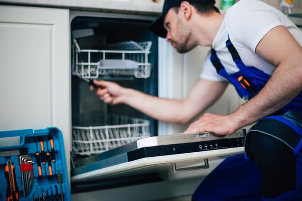 iStock Credit: Povonzniuk An appliance technician inspecting a dishwasher
